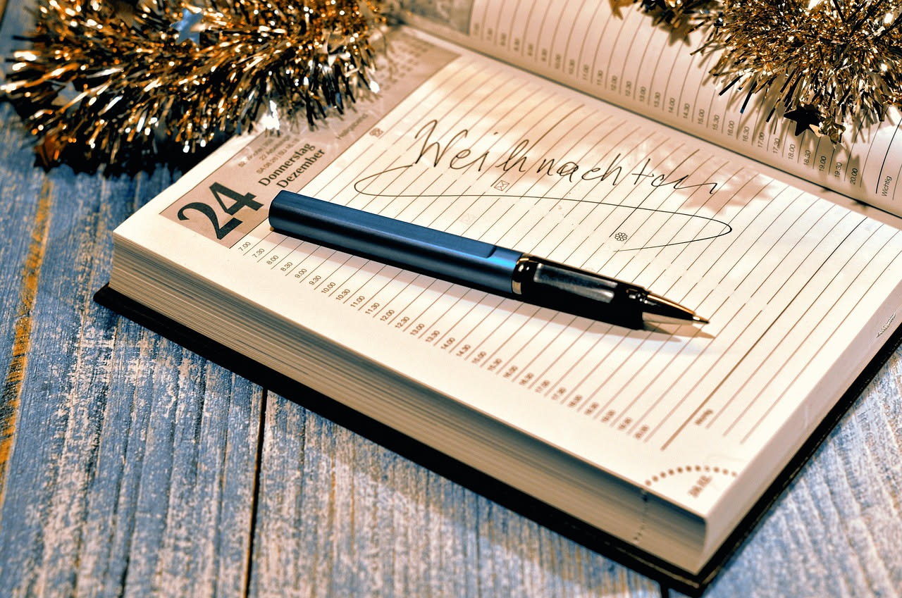 Scrivania con tazza di caffè fumante, foglio di carta bianca e penna stilografica accanto a una foto di famiglia ricordo di Natale