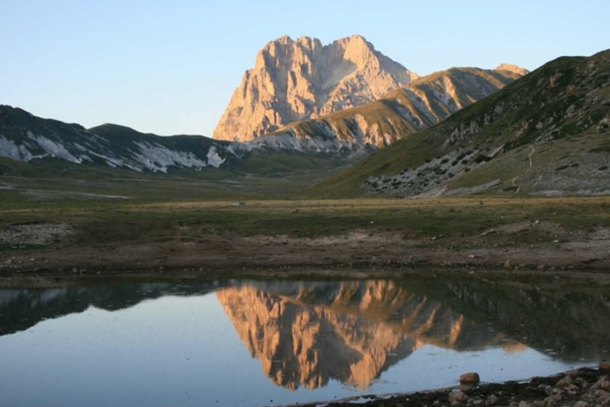 Guida ambientale coi binocoli di fronte a una valle montana con vette di marmo bianco delle Alpi Apuane e boschi verdi nel Parco