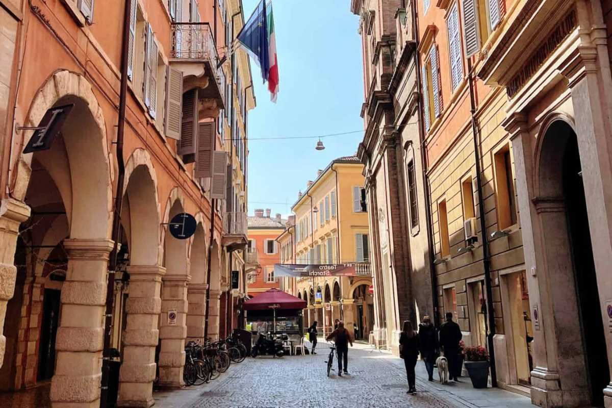 Interno di un negozio di biciclette elettriche con e-bike colorate su cavalletti, monitor con grafici e mappe della città di Padova sullo sfondo, vista diurna e luminosa