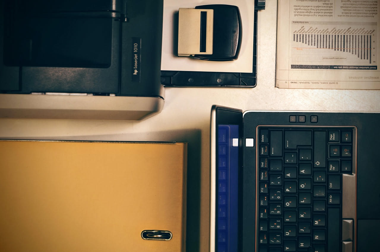 Computer portatile con schermo che mostra documento scannerizzato e frecce colorate che indicano parole evidenziate in rosso, blu e verde su sfondo bianco