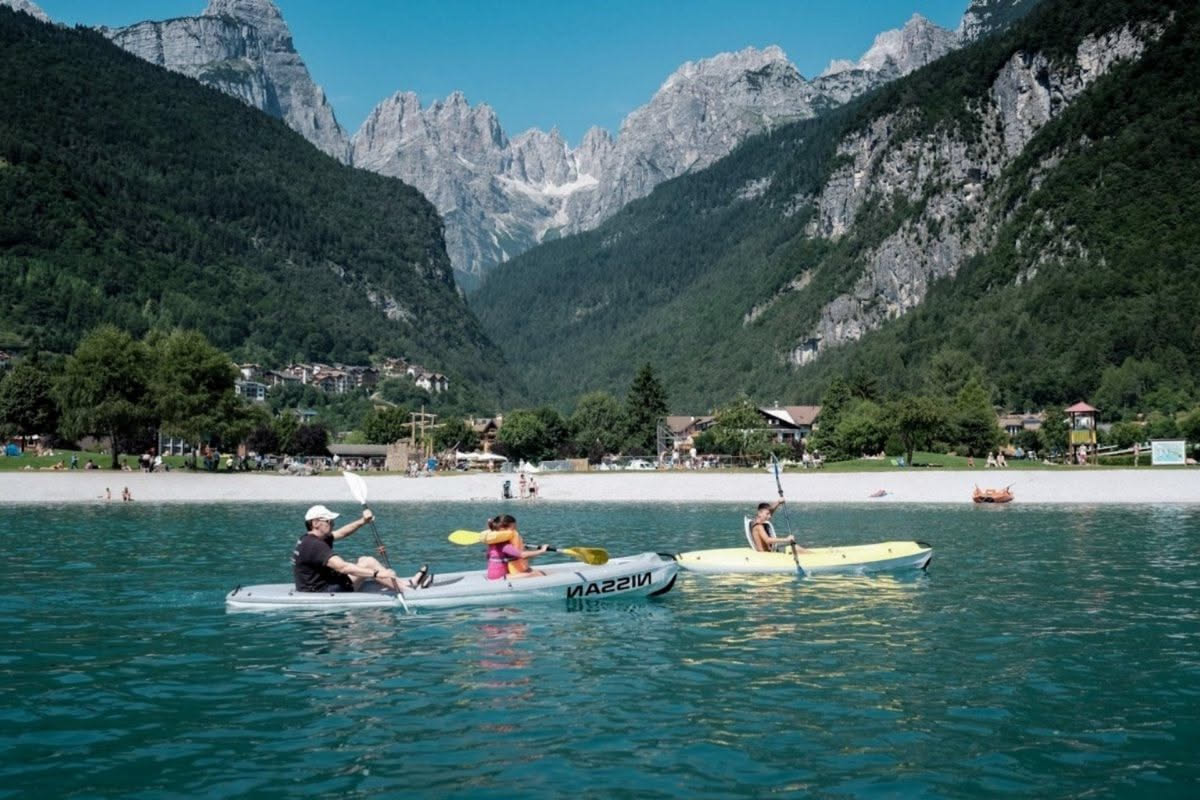 Istruttore di kayak al tramonto sul fiume nel Parco del Pollino, con canoe parcheggiate sulla sponda e montagne sullo sfondo