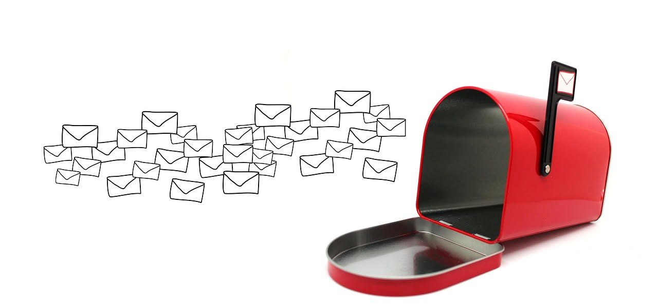 Persona al computer che scrive una email con modulo di mutuo cartaceo e calcolatrice sulla scrivania, luce naturale dalla finestra