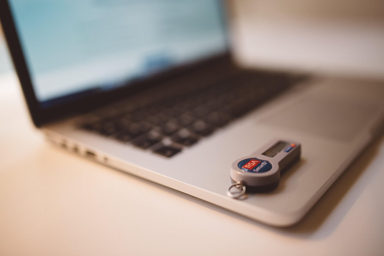 Schermo di un computer che mostra dati personali e simboli di lucchetto, icone di sicurezza e codice binario sullo sfondo, rappresentante minaccia digitale e protezione