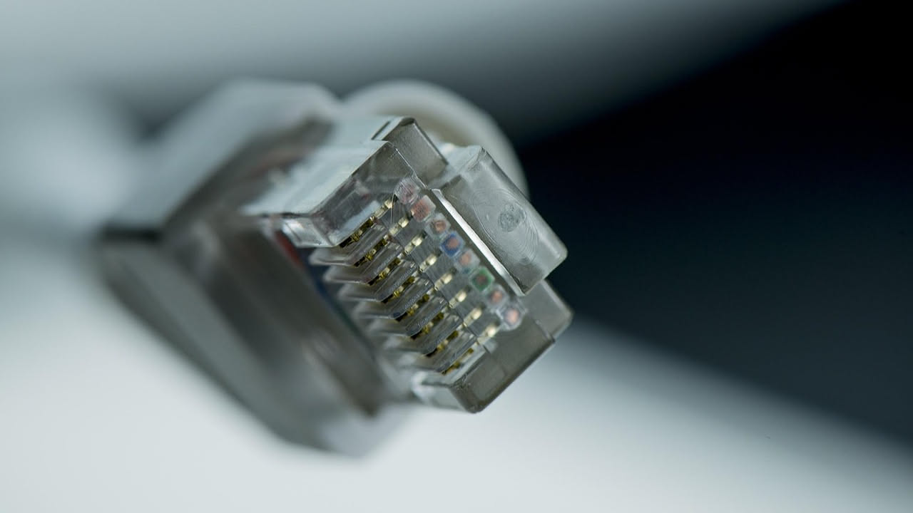 Rappresentazione di una rete globale con cavi luminosi che collegano continenti diversi, nodi di router e torri di trasmissione su sfondo blu scuro
