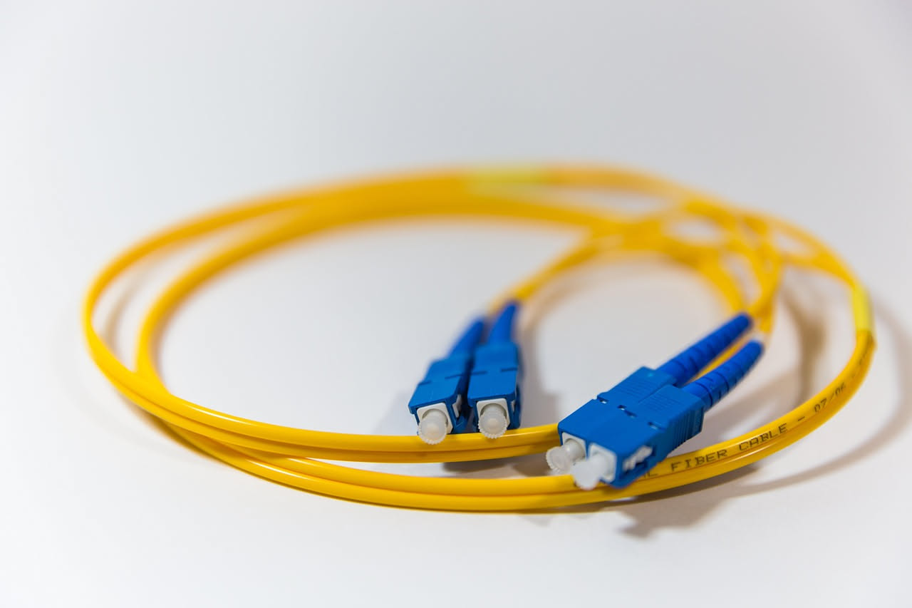 Fascio di filamenti di fibra ottica illuminati da luce rossa che brilla attraverso il vetro trasparente su sfondo nero sfocato
