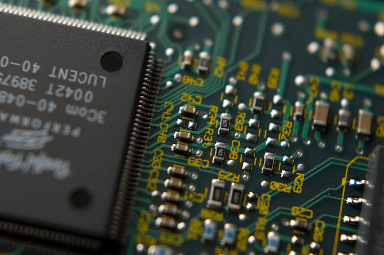 Primo piano di un microchip con circuiti dorati e tracce argentate su una superficie verde, fotografia in dettaglio tecnico