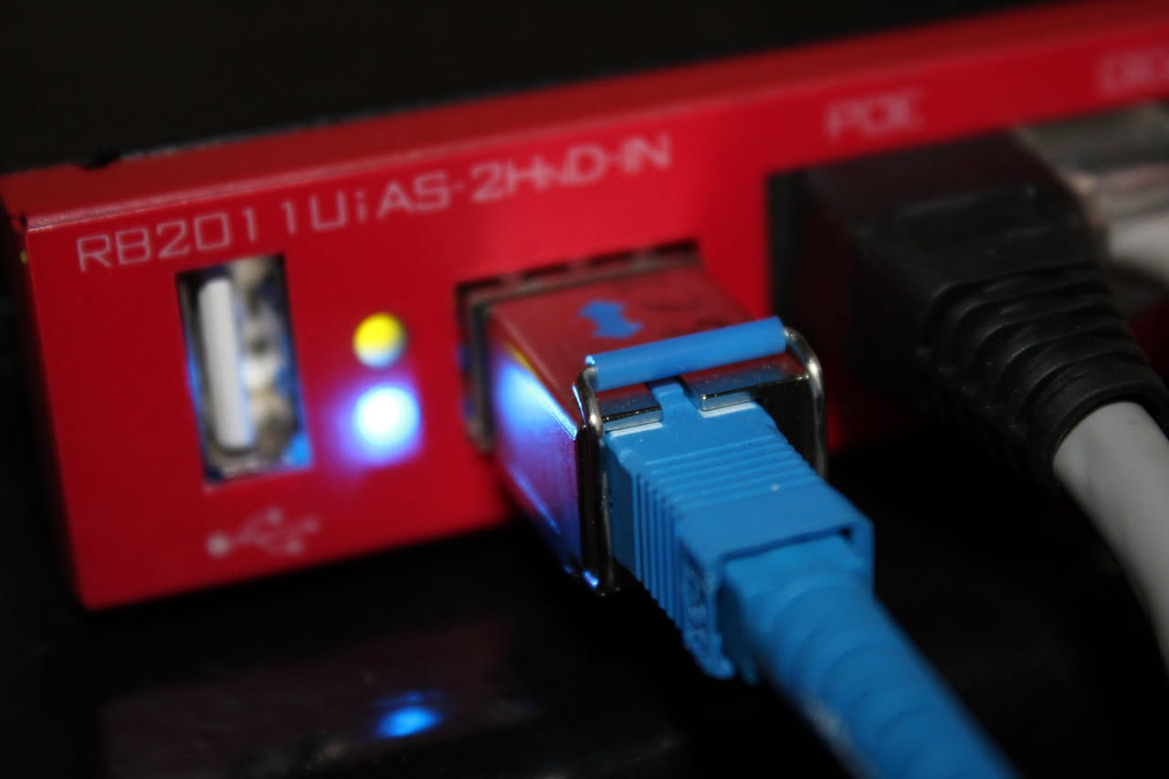 Rappresentazione schematica di un firewall come muro digitale blu con cerchi e linee di dati che passano attraverso un'apertura controllata, su sfondo nero con simboli di sicurezza