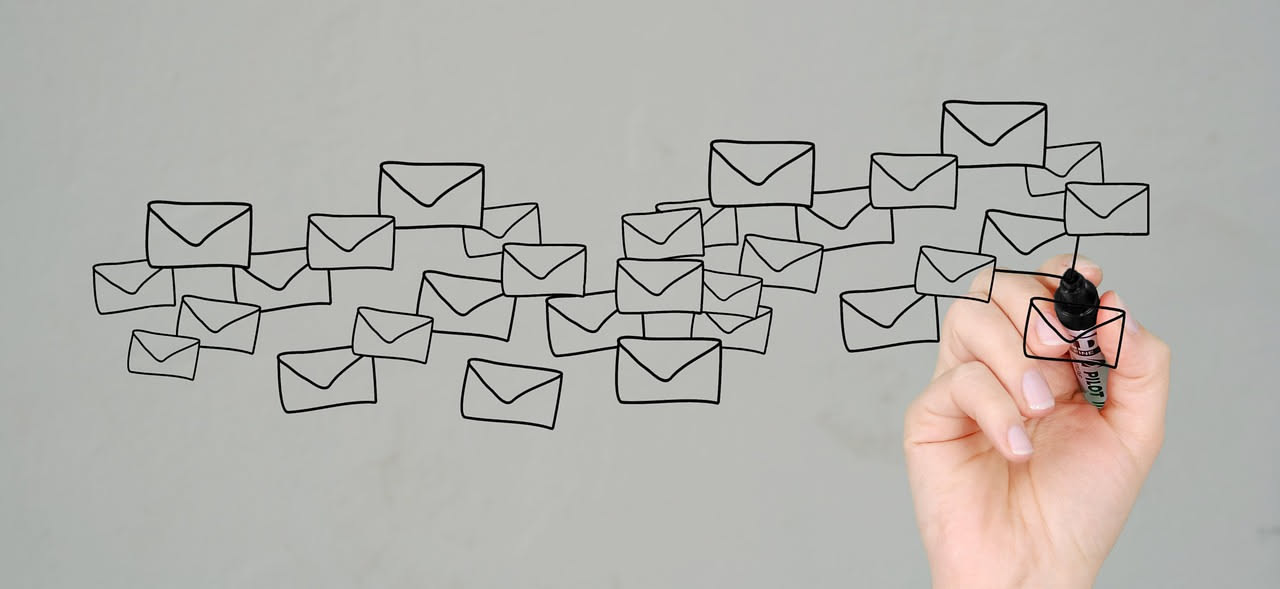 Donna al computer che scrive una mail di lavoro, con schermo diviso tra il testo originale e la versione corretta, tonalità blu e bianca minimale